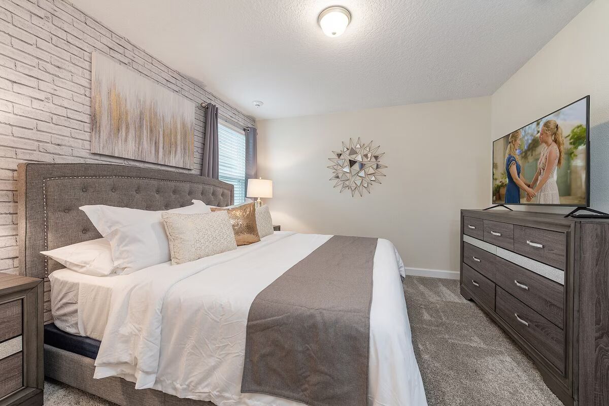 Cozy modern bedroom with stylish decor, plush bedding, and a smart TV.